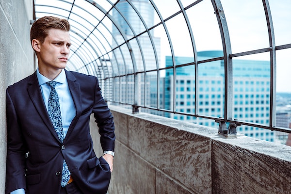 man with a defined jawline in a suit perked up against the wall