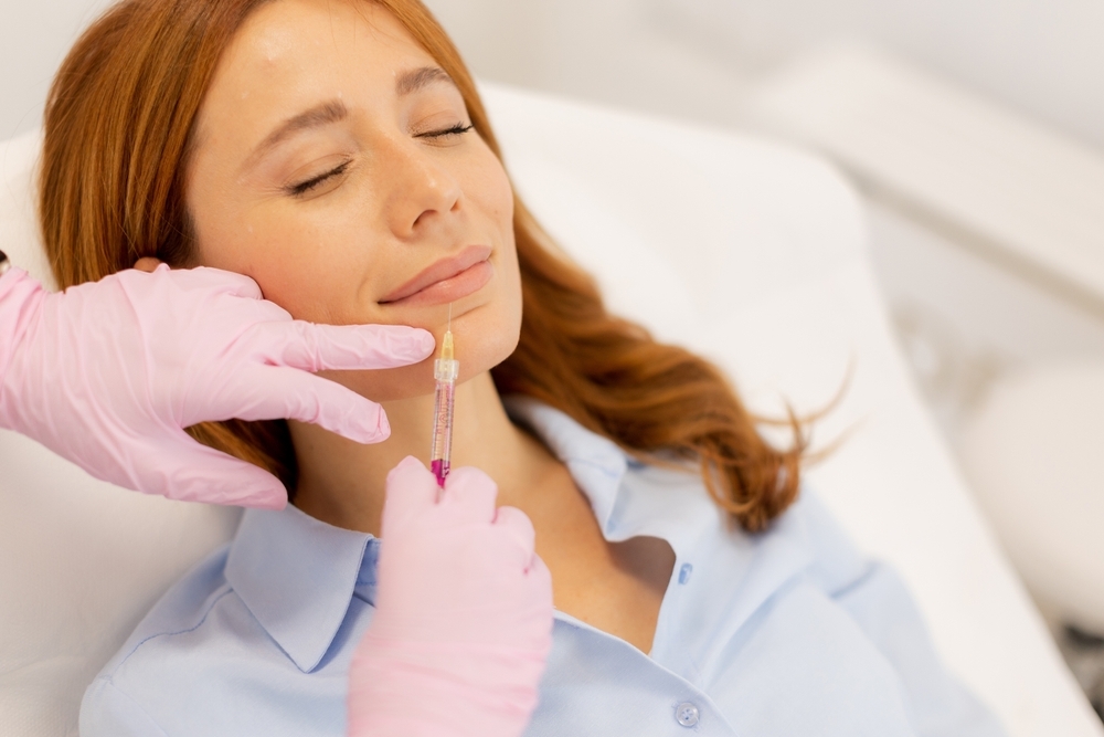 A person receives a cosmetic injection, with a medical professional wearing pink gloves administering treatment in a clinical setting