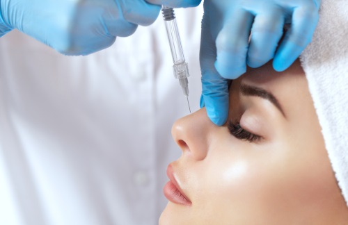 A gloved hand prepares a syringe for a medical procedure, focusing on precision and care in a clinical setting.